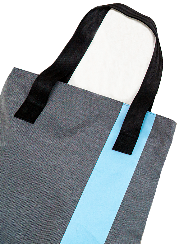 Lifestyle image of gray and blue travel set including cosmetic bags, a tote bag and glasses holder